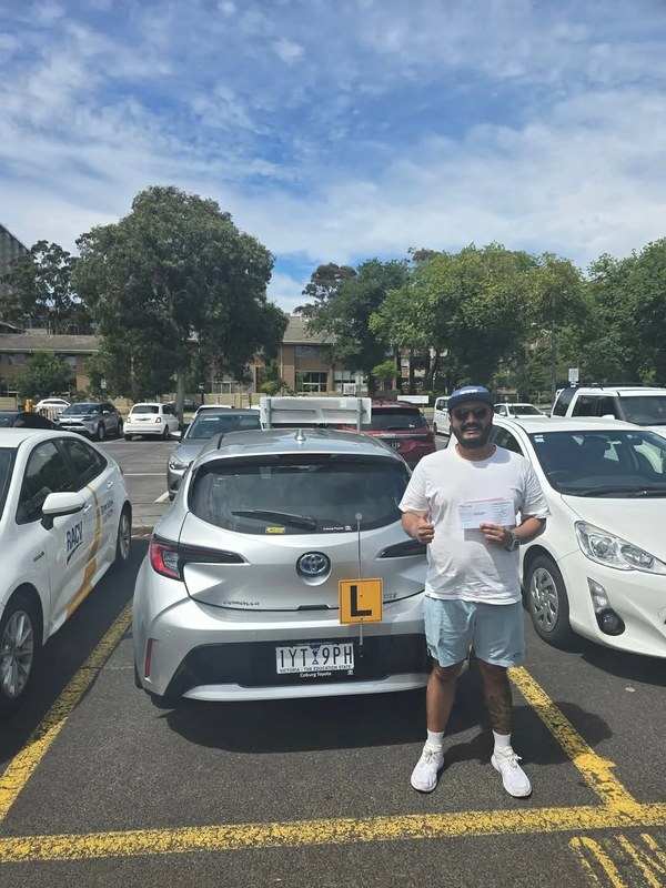 Happy student holding P plates after passing VicRoads test with Freshers Driving School Melbourne